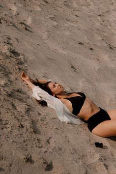 a woman laying on top of a sandy beach