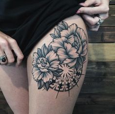 a woman's thigh with black and white flowers on the side, in front of a wooden wall