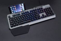 a computer keyboard sitting on top of a table next to a cell phone and tablet