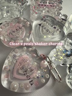 several clear heart shaped dishes with words written on them and charms attached to the lids