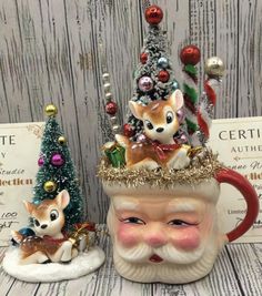 two ceramic christmas mugs sitting next to each other on top of a wooden table