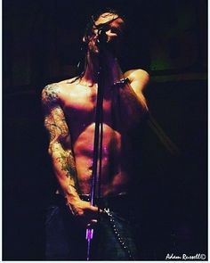 a shirtless man holding a microphone in front of his face while standing on stage