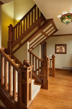 a wooden stair case in a home with stained glass window above the bannister