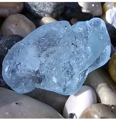 a blue rock sitting on top of rocks covered in water and ice flakes