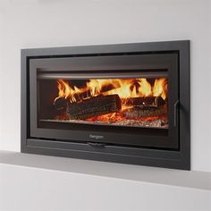 a fire burning in a fireplace next to a white wall