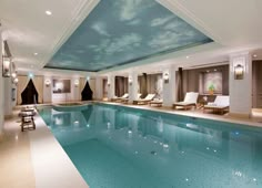 a large indoor swimming pool with lounge chairs around the edge and sky painted on the ceiling