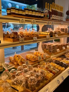 a display case filled with lots of different types of bread and pastries in plastic bags