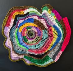 a multicolored crocheted doily on a black surface