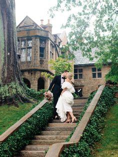 a bride and groom are kissing on the steps in front of an old house with ivy growing around it