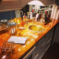 a counter top with a sink and various bottles on it in a home bar area