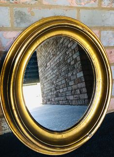 a gold circular mirror sitting against a brick wall