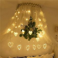 a white bed topped with lots of lights next to a window