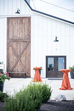 an outdoor wedding venue with orange linen draped over the doors and flowers in vases