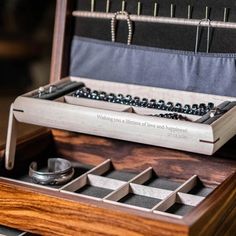 an open wooden box with beads and rings in it