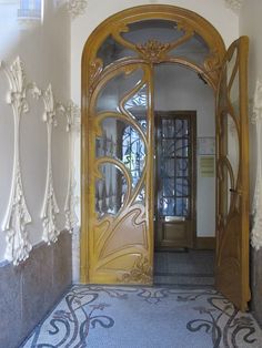 an ornate wooden door with glass panels on the front and side doors are open to let in light