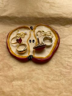 two pairs of rings are sitting in an apple shaped box with gold and red accents