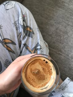 a person sitting on a couch holding a cup of coffee