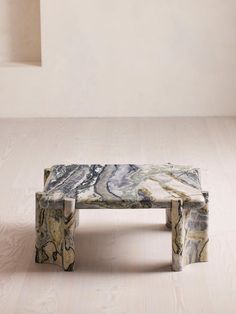 a marble bench sitting on top of a hard wood floor next to a white wall