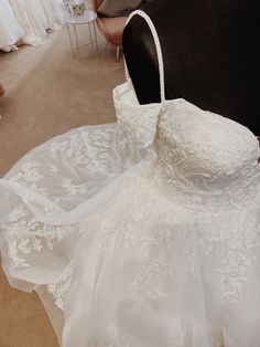 there is a white dress on display in the room with other wedding gowns behind it