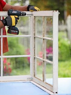 a man is working on the outside of a window with a driller and gloves