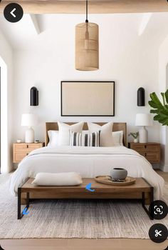 a bed with white sheets and pillows in a bedroom next to a plant on the floor