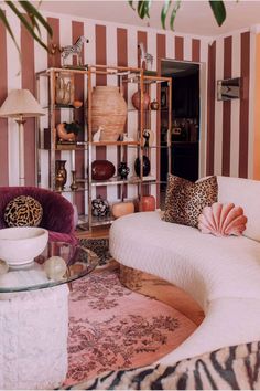 a living room filled with furniture next to a zebra print rug and a large potted plant