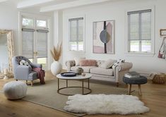 a living room filled with furniture and windows covered in shades of greys, pinks and whites