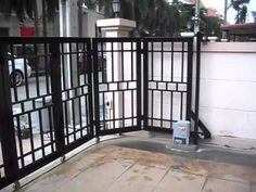 a gated area with a trash can in front of it and cars parked on the street behind it