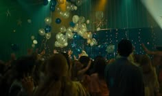 a group of people at a party with balloons and streamers flying in the air