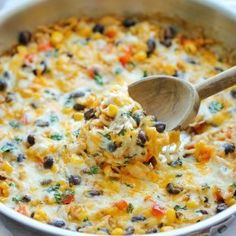 a wooden spoon scooping some food out of a casserole dish with corn and black beans