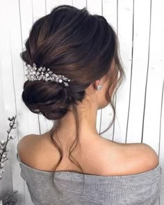 a woman wearing a hair comb with flowers in it's back and her hair pulled up into a low bun