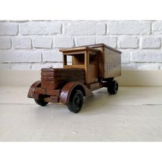 a wooden toy truck sitting on top of a white table next to a brick wall