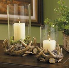 three candles are sitting on a table with rocks and antlers