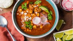 a bowl of soup with meat, onions and cilantro in it on a wooden table