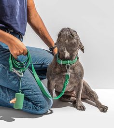 a man sitting on the floor with his dog wearing leashes and holding a cup