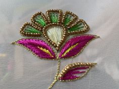 a close up of a flower on a white cloth with gold and green beads in the center