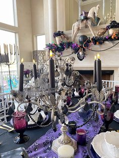 a dining room table is set with purple and white dishes, candles, and decorations