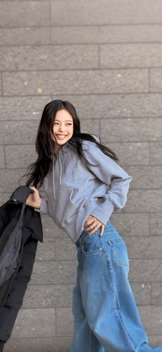 a young woman is walking down the street with her coat over her shoulder and smiling