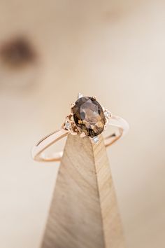 a close up of a ring on top of a wooden stand with a brown diamond