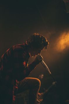 a man sitting on top of a stool holding a microphone in front of his face