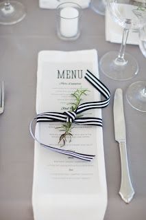 the table is set with black and white striped napkins, wine glasses, silverware