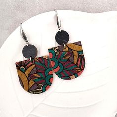 a pair of wooden earrings sitting on top of a white plate