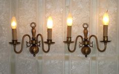 three light wall sconces with candles on them