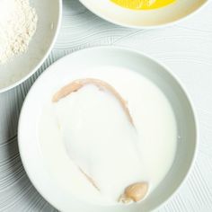 two bowls filled with milk and oranges on top of a white table cloth next to each other