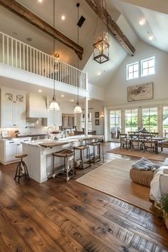 a large open concept kitchen and dining room with wood floors, white cabinets and high ceilings