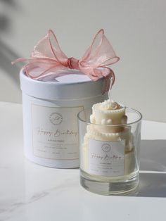 a candle with a pink bow on it next to a small glass container filled with soap