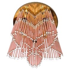 a pink chandelier hanging from the ceiling with beads and pearls on it's sides