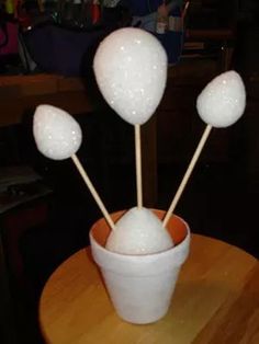 four white cotton swabs in a vase on a table