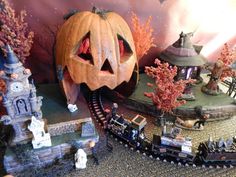 there is a fake pumpkin on top of the train tracks in this miniature town scene