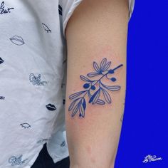 a tattoo on the arm of a woman with an olive branch and leaves in blue ink